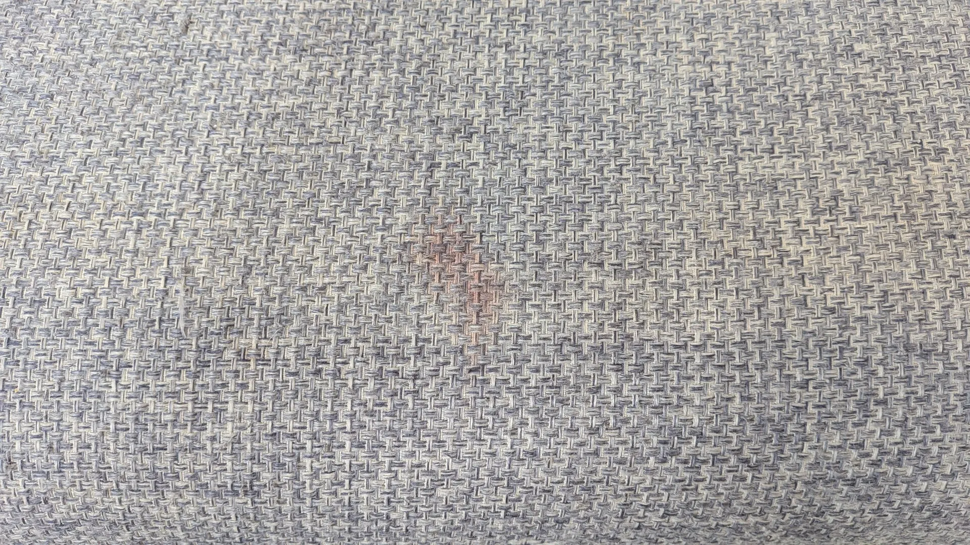 織り目に赤茶色がにじんだシミの接写