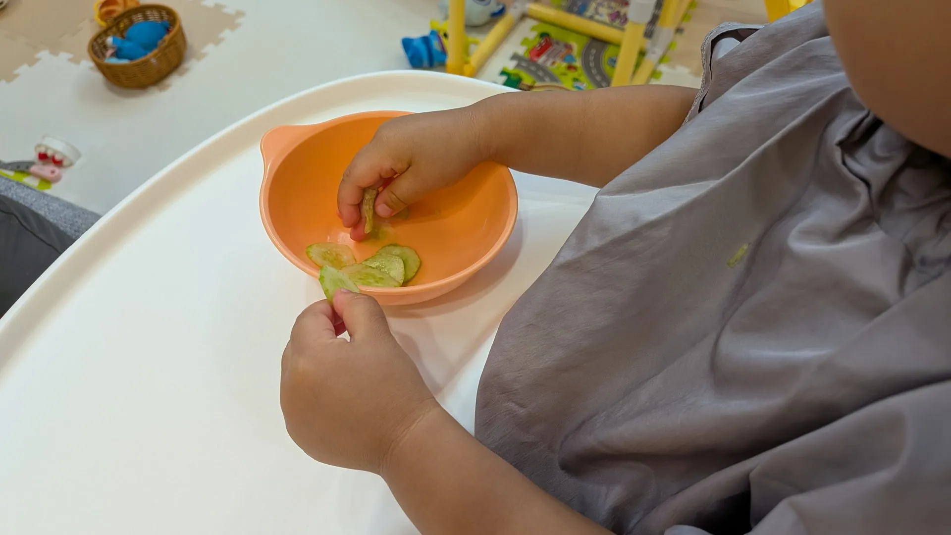子ども椀から薄切りきゅうりを手づかみで取る小さな手