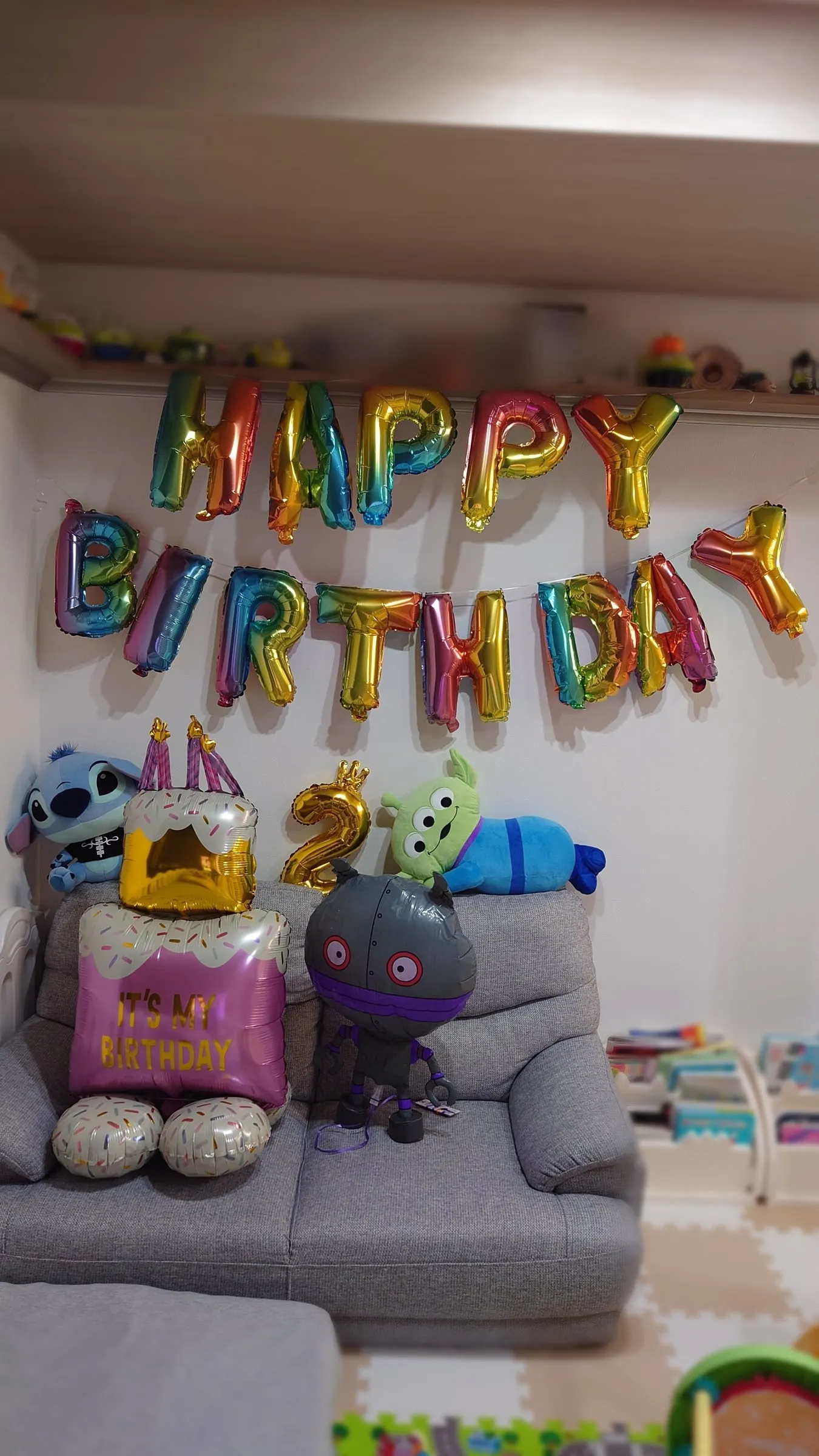 壁に飾った虹色のHAPPY BIRTHDAYバルーンと、金色の2の風船、ケーキ型の風船、ぬいぐるみたち