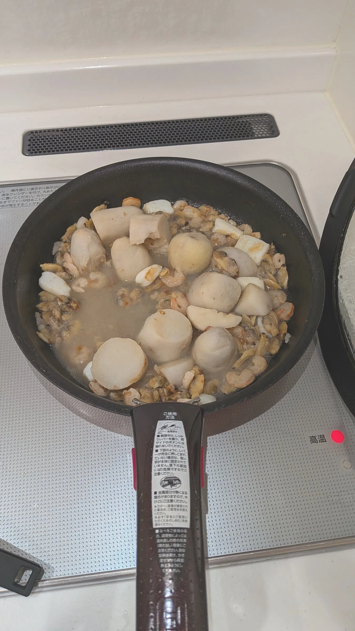 真上から見たフライパン。煮汁の中に里芋がごろごろと入り、まわりにえび・あさり・いかが広がっている