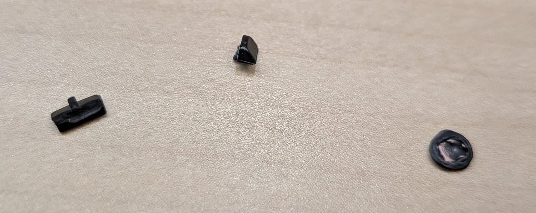 Dell の内部から出てきた部品3点。折れたツメの破片とゴム足
