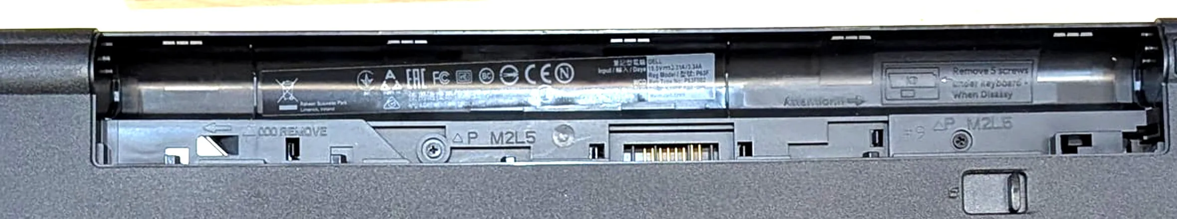 Dell のバッテリーを外した奥の拡大。ODD REMOVE の矢印、P M2L5 のマーク付きネジ2本、Remove 5 screws under keyboard の刻印